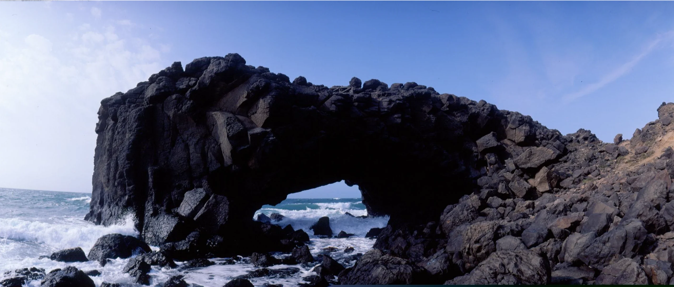 Xiaomen Whale Cave sea arch and stone walkway along the basalt coastline of Penghu, Taiwan.